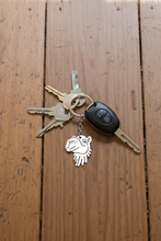 Load image into Gallery viewer, Set of keys with a camel keychain attached sitting on wooden floorboards