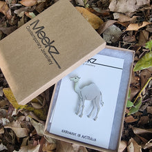 Load image into Gallery viewer, Meekz Contemporary Jewellery packaging with an aluminium camel brooch on a white card, in a box, surrounded by leaves.