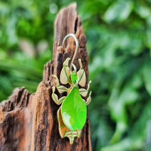 Load image into Gallery viewer, Leaf insect earrings - the image shows a leaf mimicking insect earring crafted from lime‑green car vinyl with recycled brass detailing, sterling‑silver hook, and hypoallergenic stainless‑steel jump rings, shown hanging against natural wood with a soft green outdoor background. It is a side on perspective.