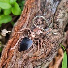 Load image into Gallery viewer, Meat‑ant–inspired earring made from black car vinyl with recycled copper body segments, a sterling‑silver hook, and a hypoallergenic stainless‑steel jump ring, displayed on textured wood with soft green leaves in the background.