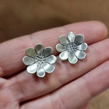 Load image into Gallery viewer, Paper Daisy Studs modelled sitting between Jemica's fingers on her hand for size comparison