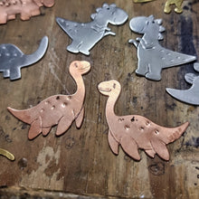 Load image into Gallery viewer, Copper Plesiosaur dinosaur-shaped earrings on a wooden jewellers bench surrounded by other dinosaurs