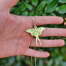 Load image into Gallery viewer, Luna moth necklace hanging on my hand