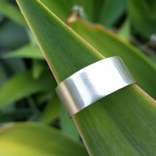 Load image into Gallery viewer, 10mm sterling silver band with no texture modelled on a leaf