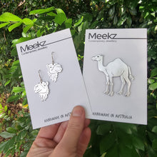 Load image into Gallery viewer, Handmade silver earrings and brooch on display with 'Meekz' packaging against a green leafy background.
