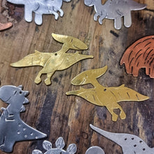 Load image into Gallery viewer, Brass Pterodactyl (Flying) dinosaur earrings on a wooden jewellers bench surrounded by other dinosaurs
