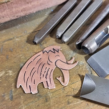 Load image into Gallery viewer, Metalworking tools and a copper woolly mammoth shaped dinosaur on a wooden surface
