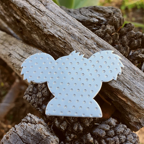 Aluminium Koala Brooch sitting on a wooden fence